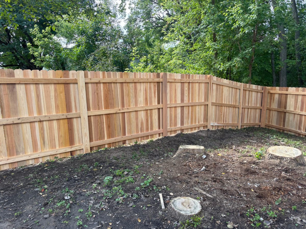 Cedar privacy fence enclosing backyard with freshly cleared dirt landscaping