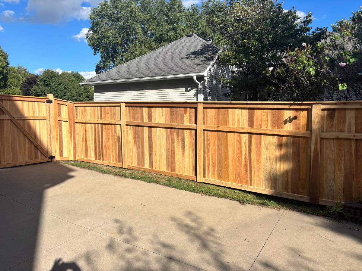Cedar privacy fence along concrete driveway beside house
